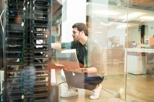 Network administrator with notebook computer sitting in data center room