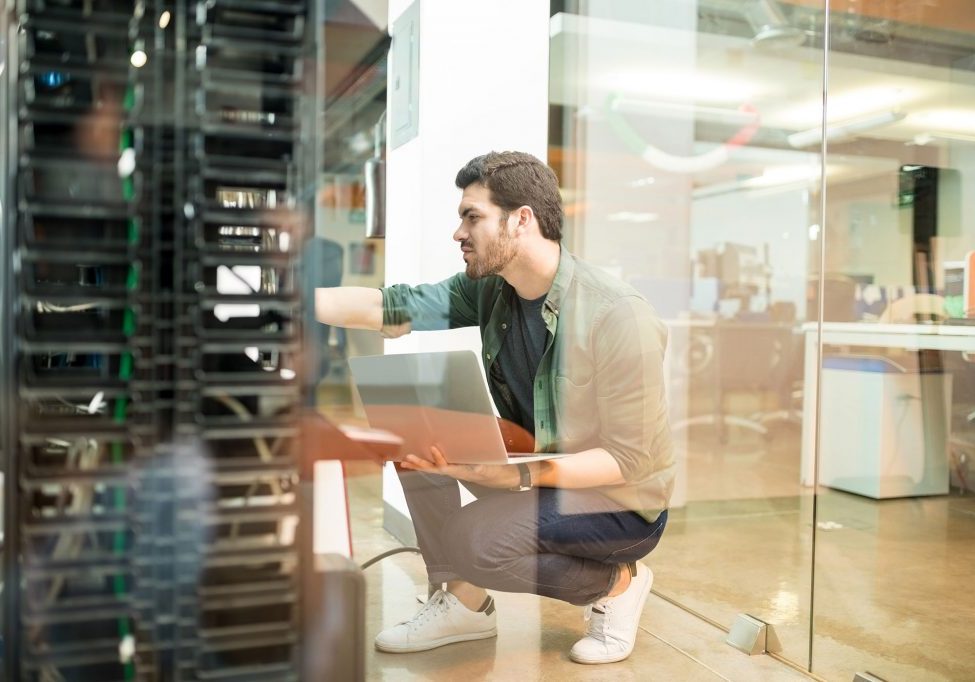 Network administrator with notebook computer sitting in data center room